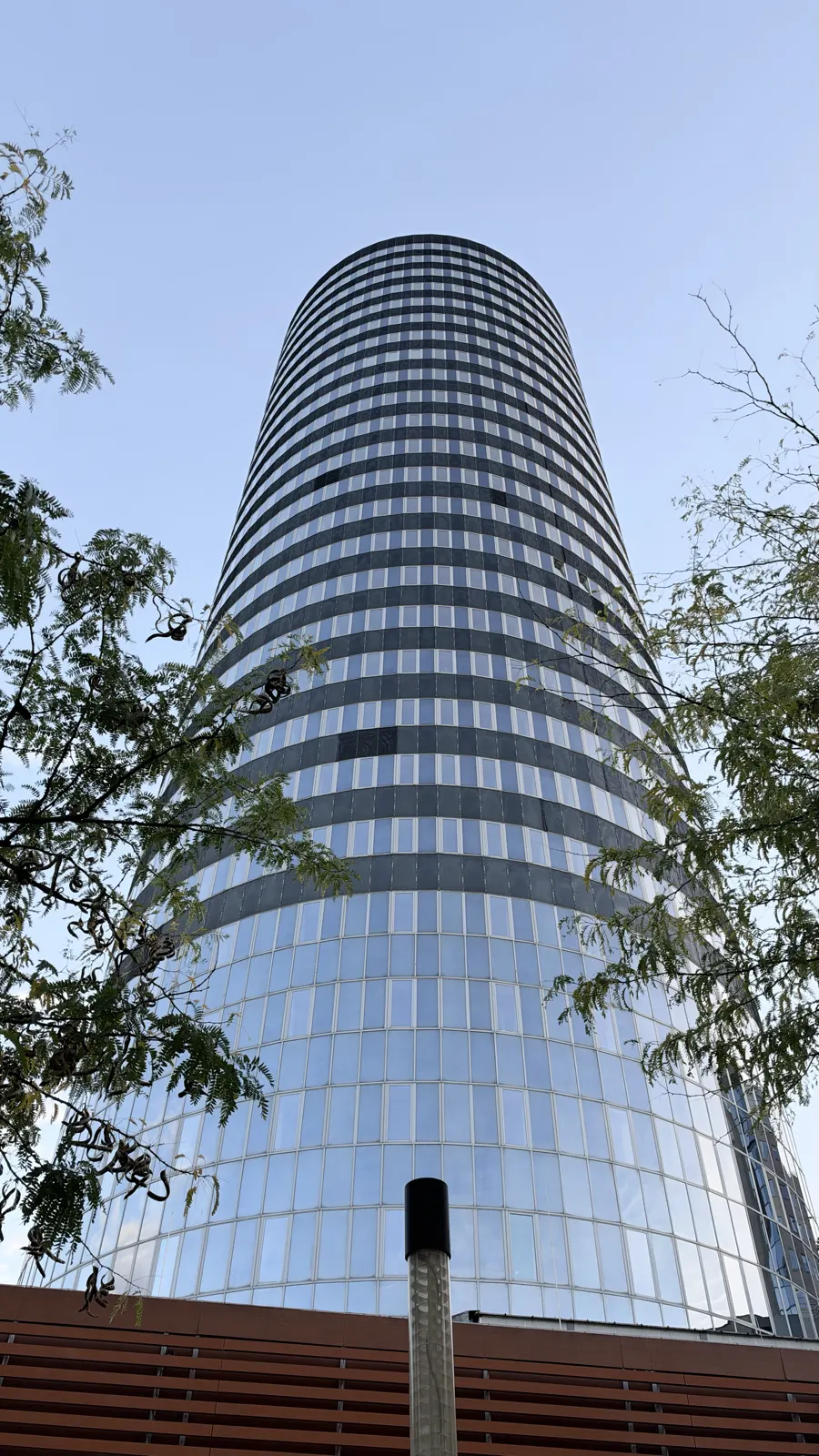 Der JenTower, ein runder Hochhausturm mit Glasfassade, von unten gesehen