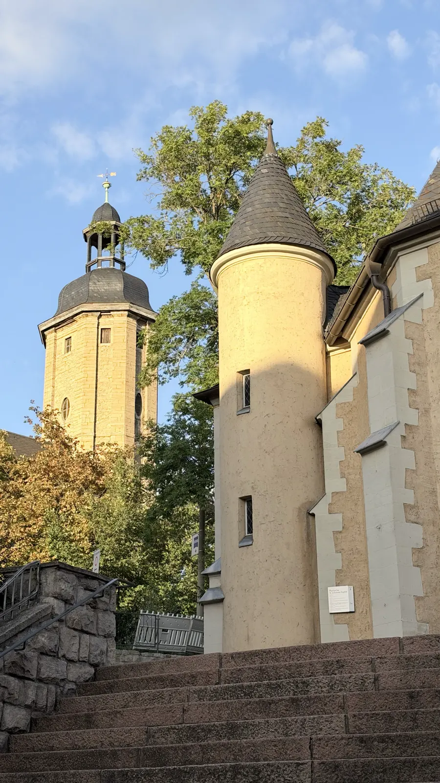 Treppenaufgang mit einem kleinen Rundturm, dahinter der Turm der Stadtkirche St. Michael